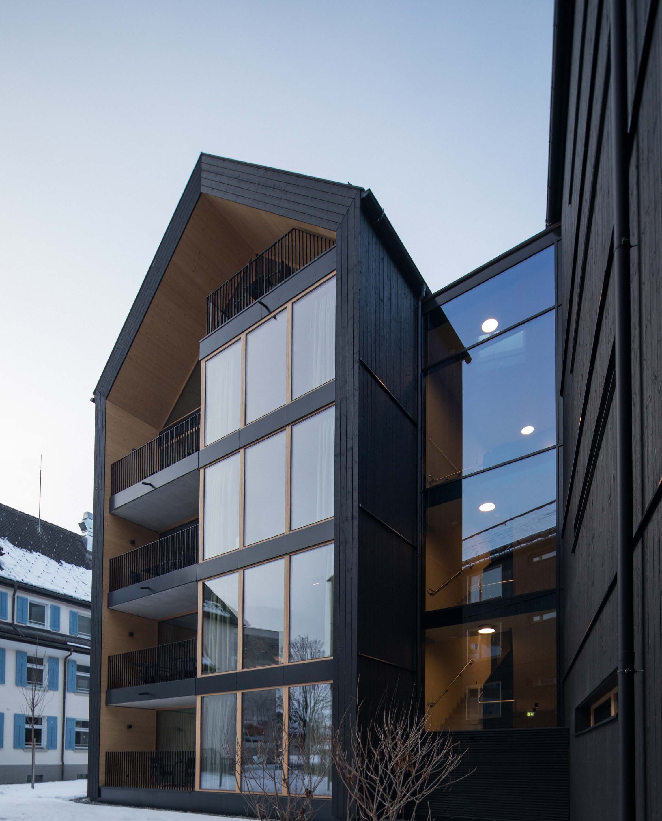 SUITES Montafon im Winter, schwarze Holzfassade mit Giebel, Balkonen und Glasfront