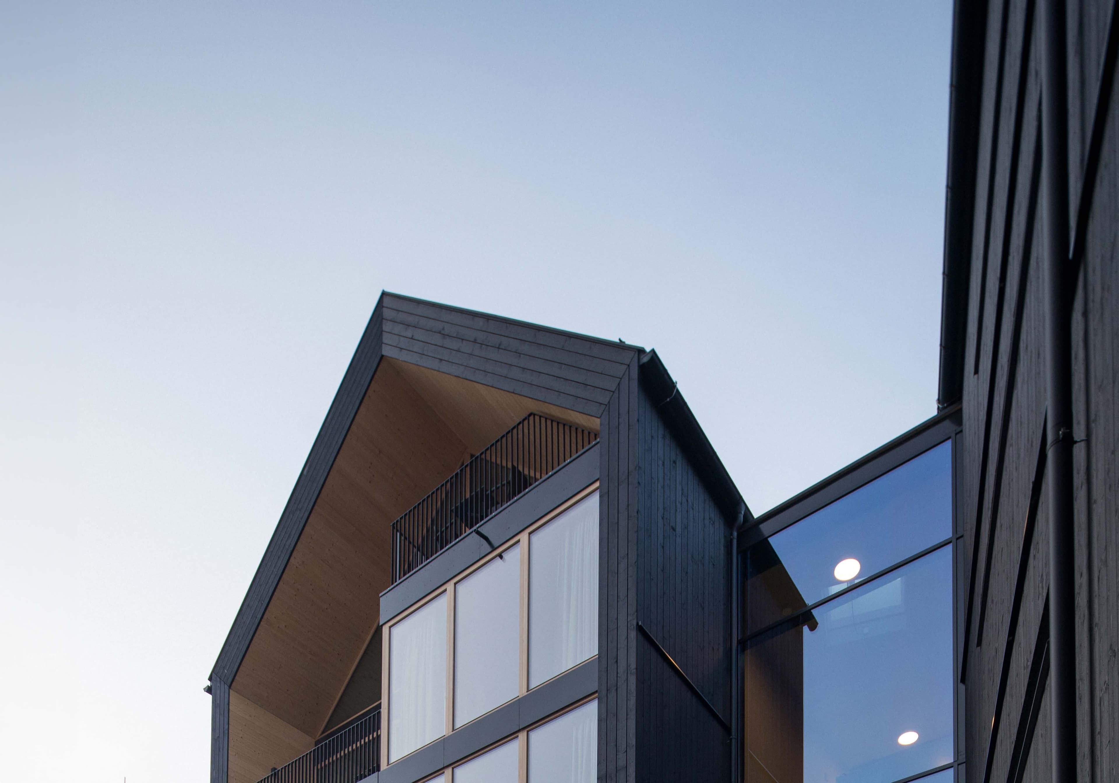 Giebel der SUITES Montafon mit schwarzer Holzfassade und Glasfront vor dem Abendhimmel