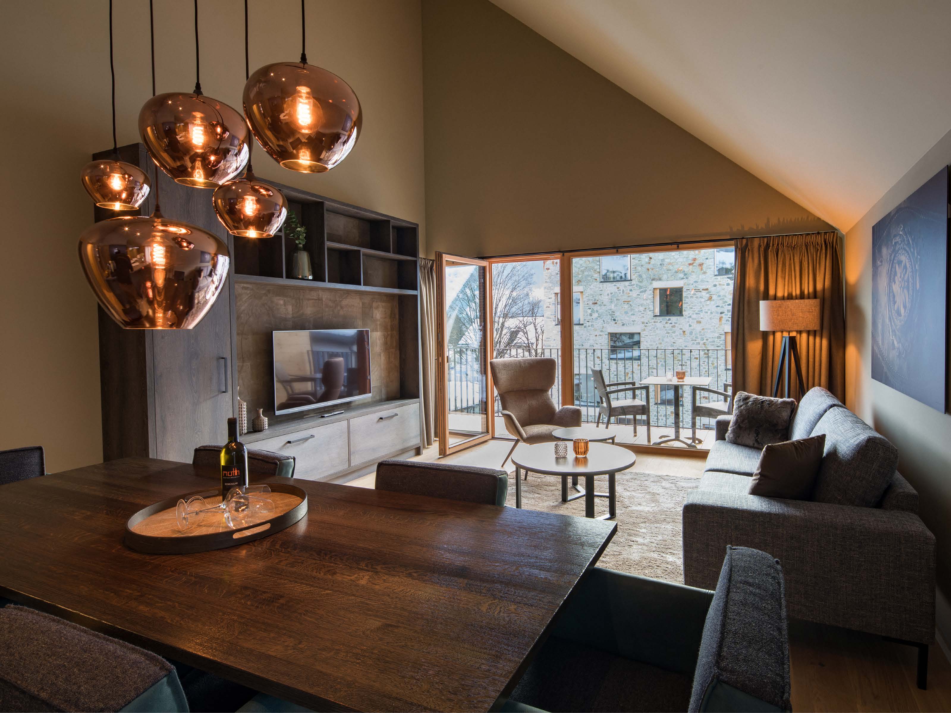 Penthouse-Wohnbereich mit Kupferpendelleuchten, Esstisch und Dachschräge