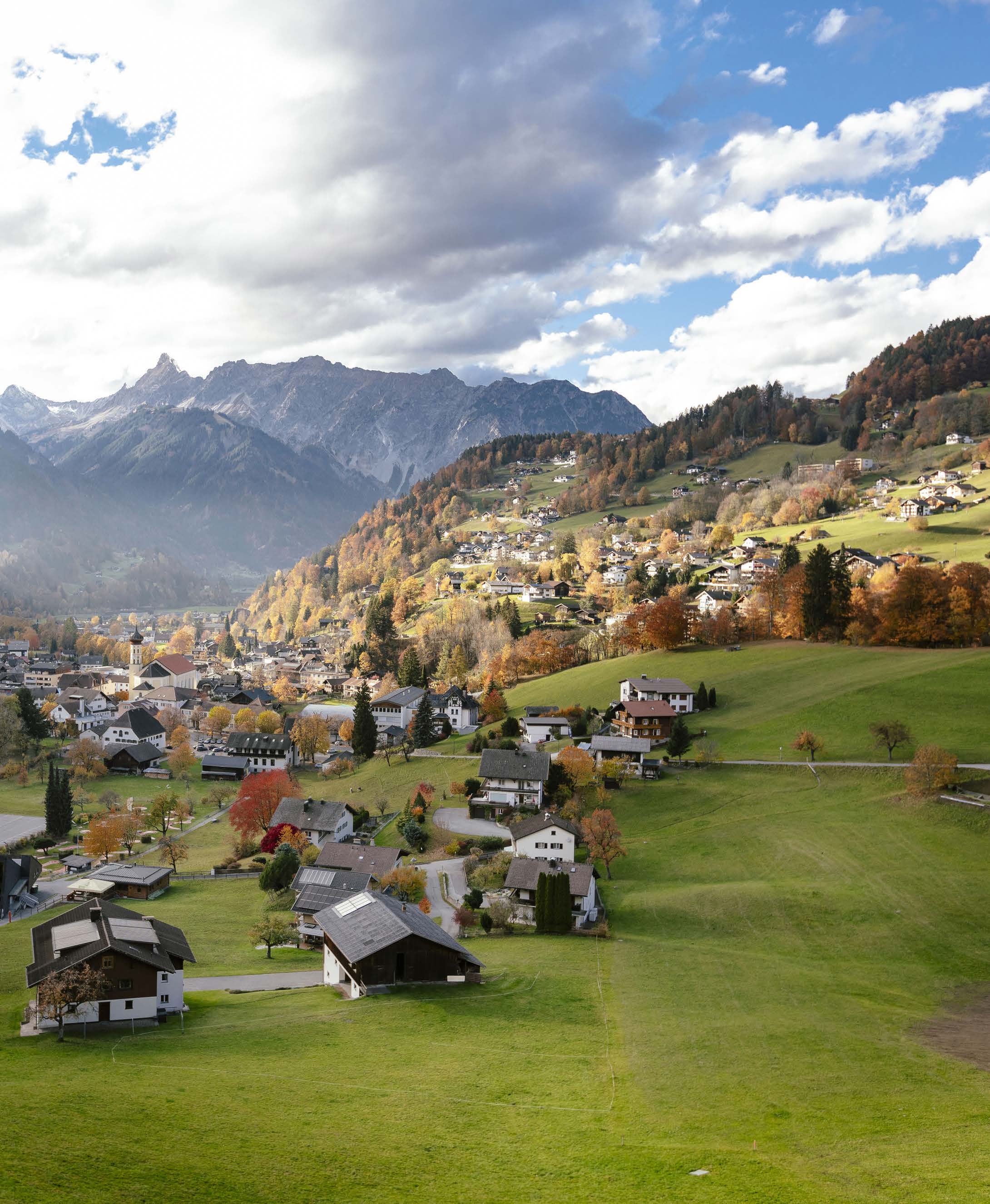 Schruns im Herbst von oben mit Kirche, Wiesen und Bergen