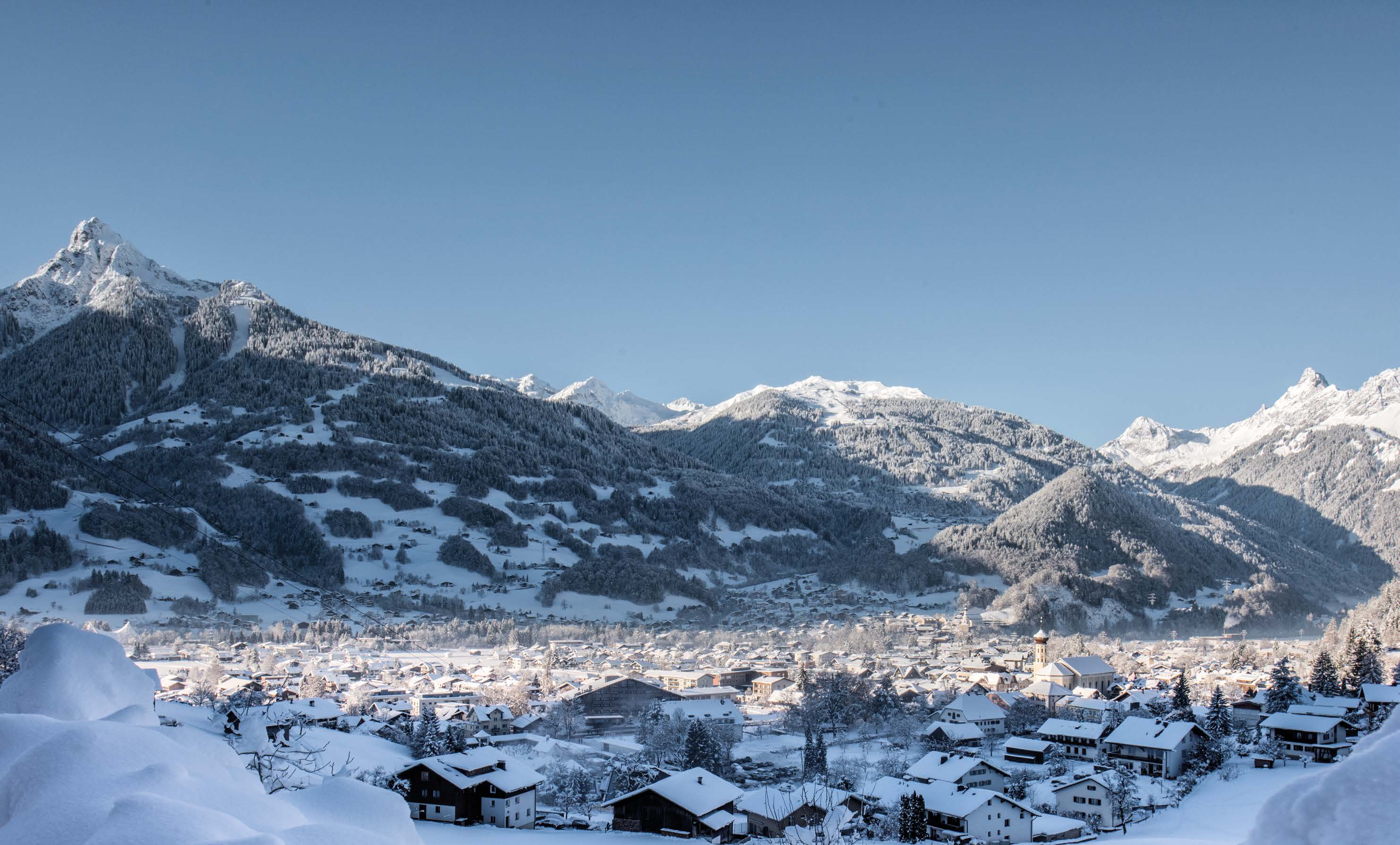 Schruns im Winter mit verschneiten Dächern und der Zimba im Hintergrund