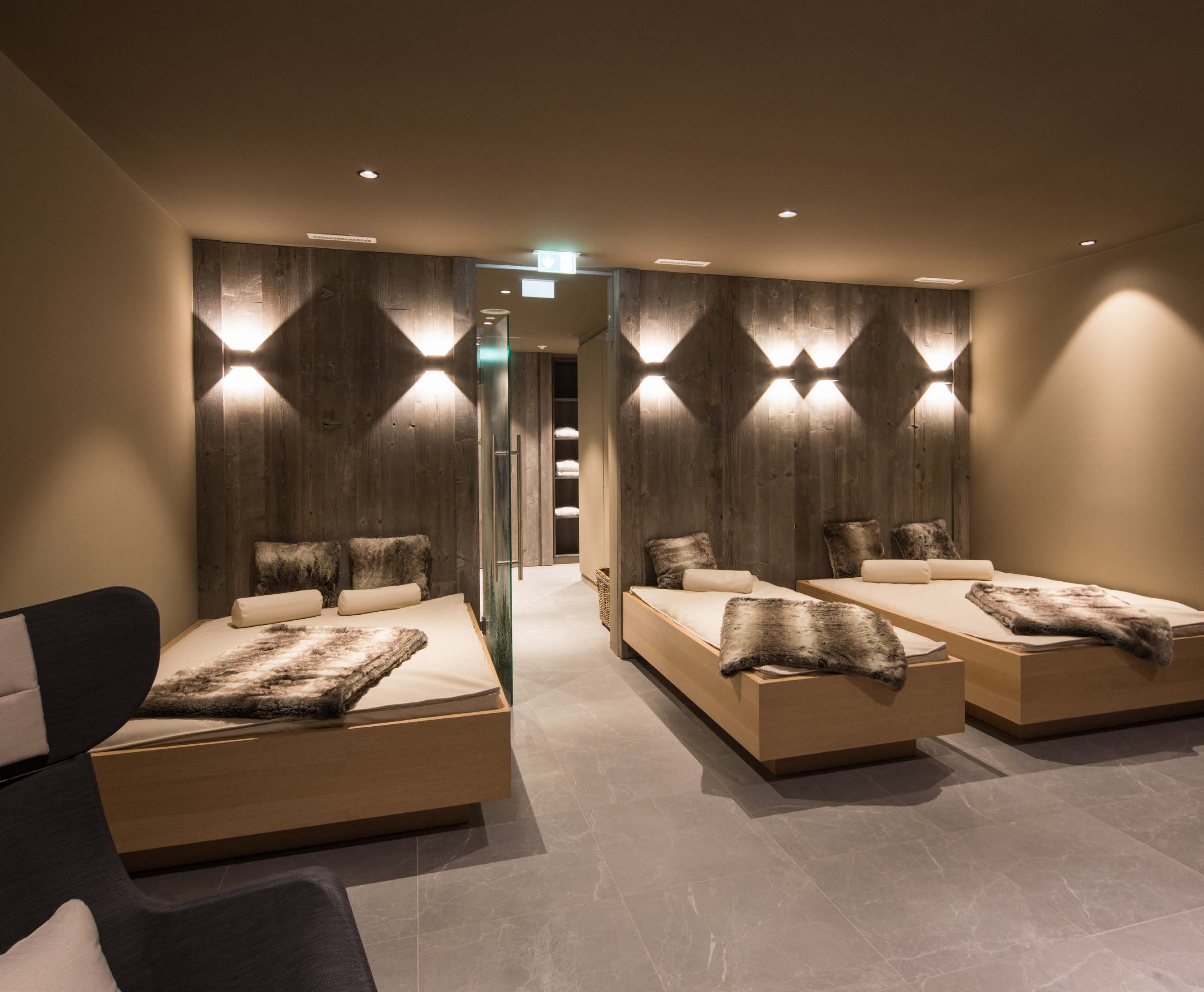 Ruheraum des Wellnessbereichs mit Wasserbetten, Felldecken und Lichtwand aus Holz